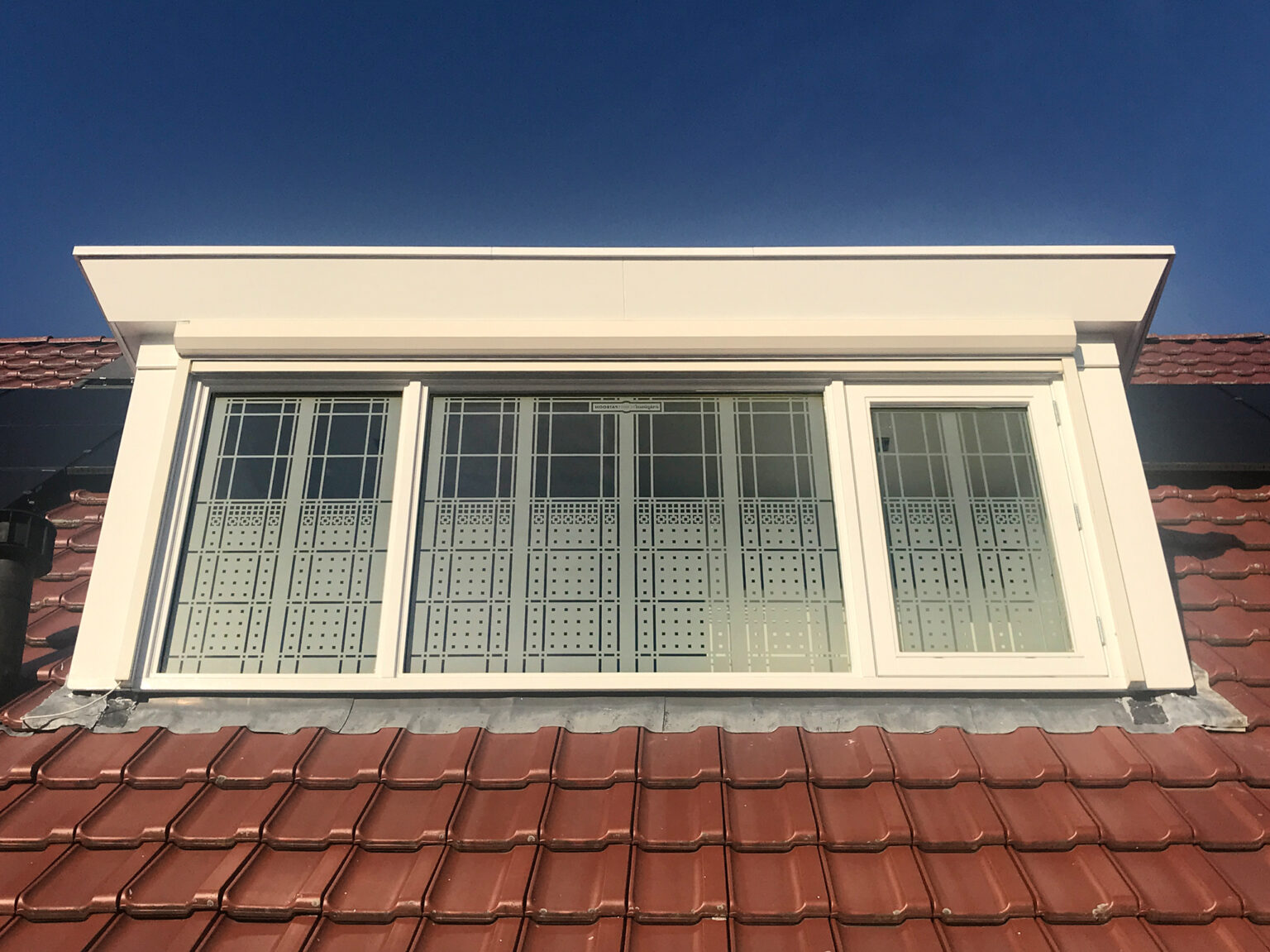 Buitenaanzicht Schutspatroon op ramen van dakkapel met badkamer.