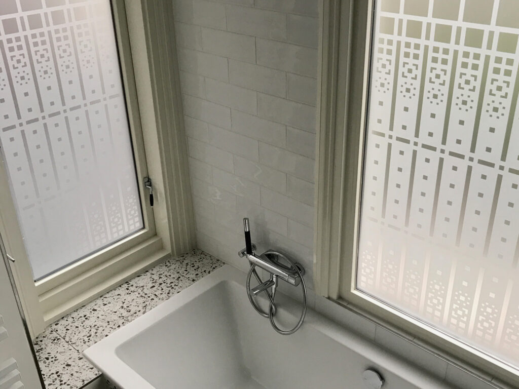 raamfolie van een Schutspatroon op badkamerramen.
