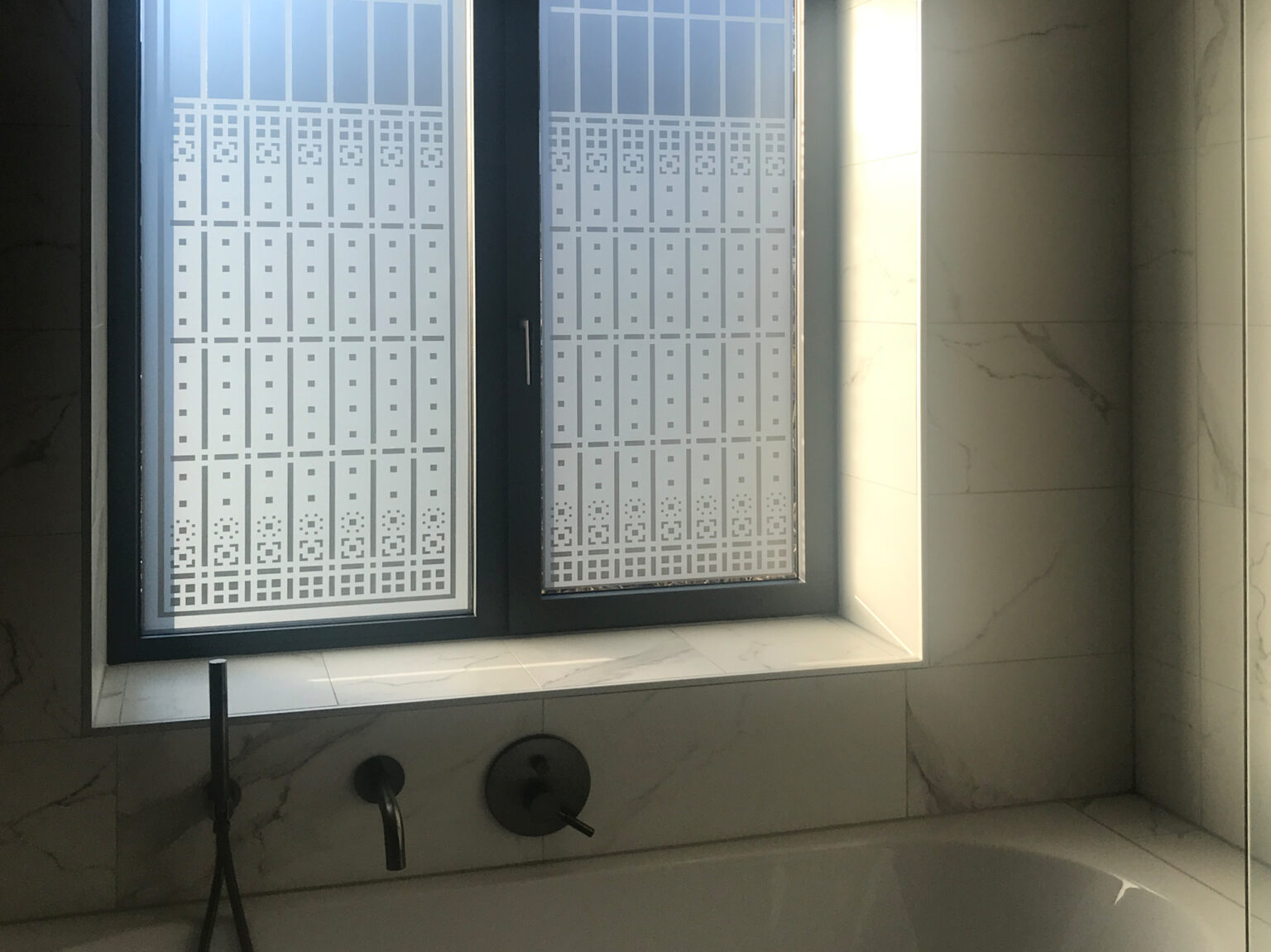 Impressie van de raamfolie van een Schutspatroon op badkamerramen.