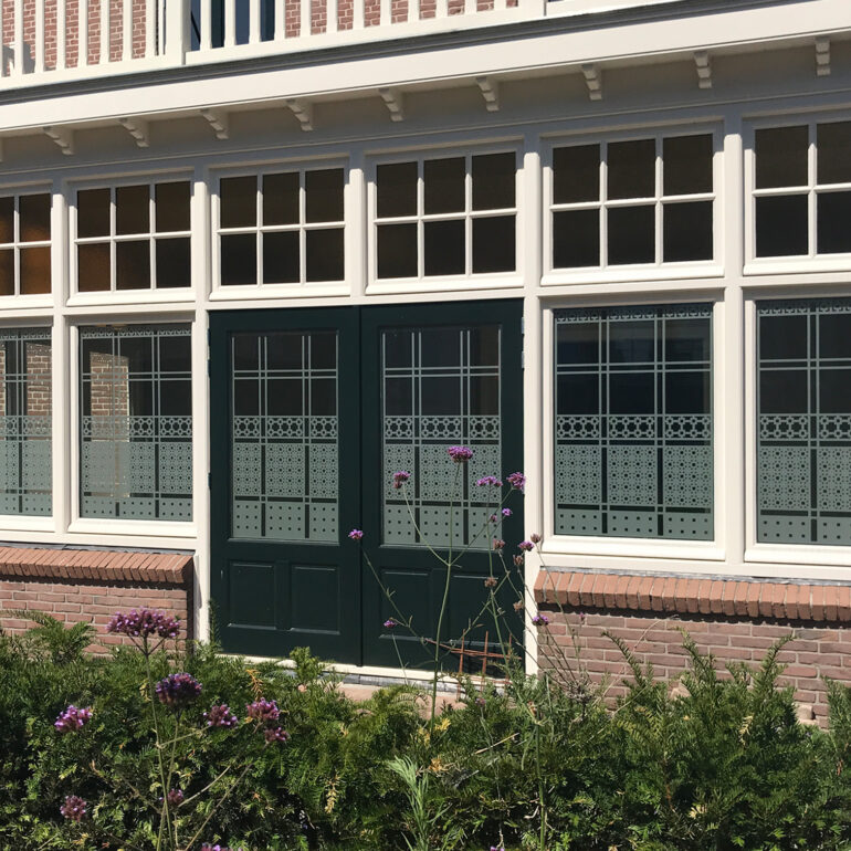 Schutspatroon op ramen serre van buiten gezien.